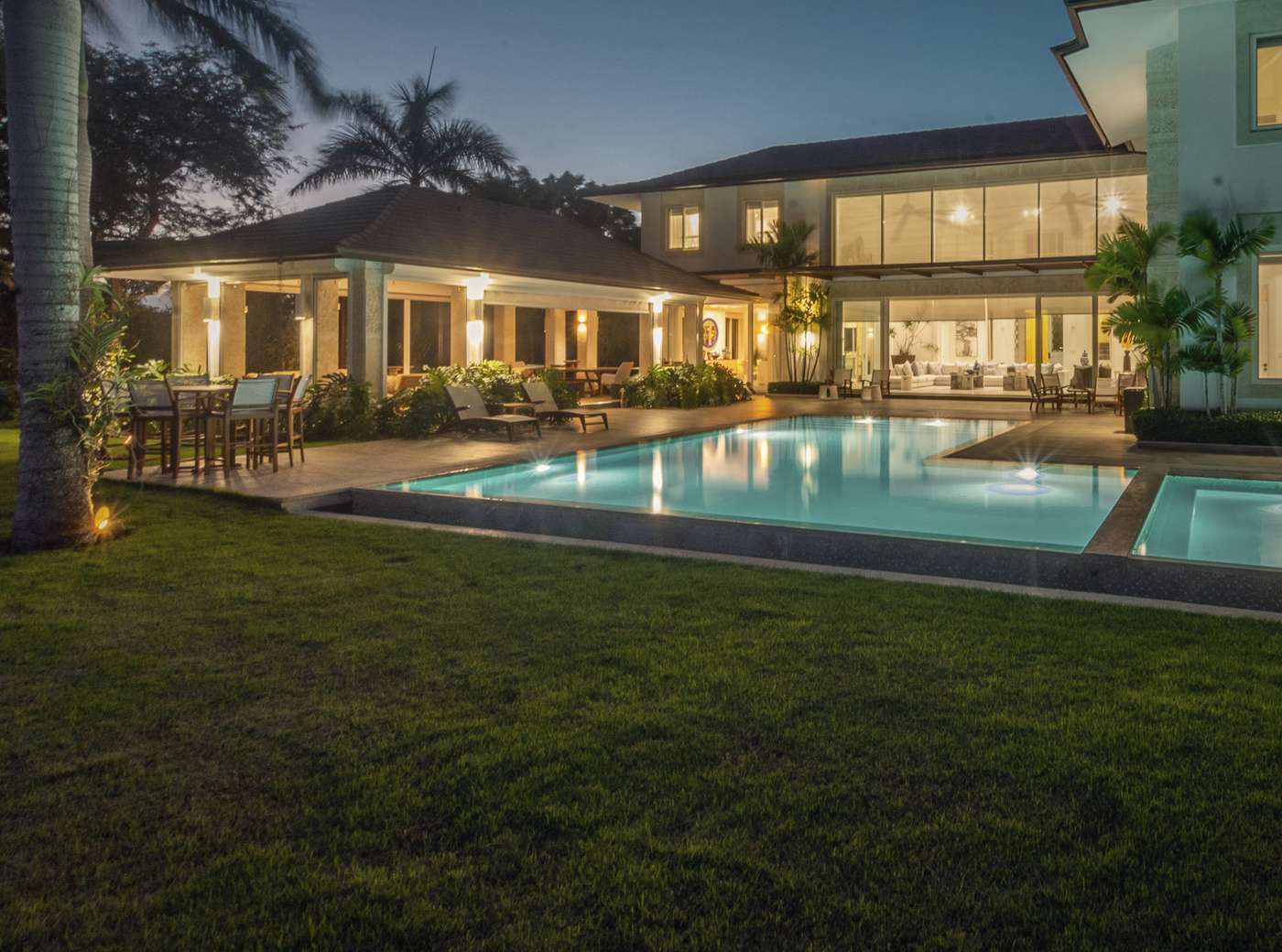A house at dusk, the pool lit and the windows warm